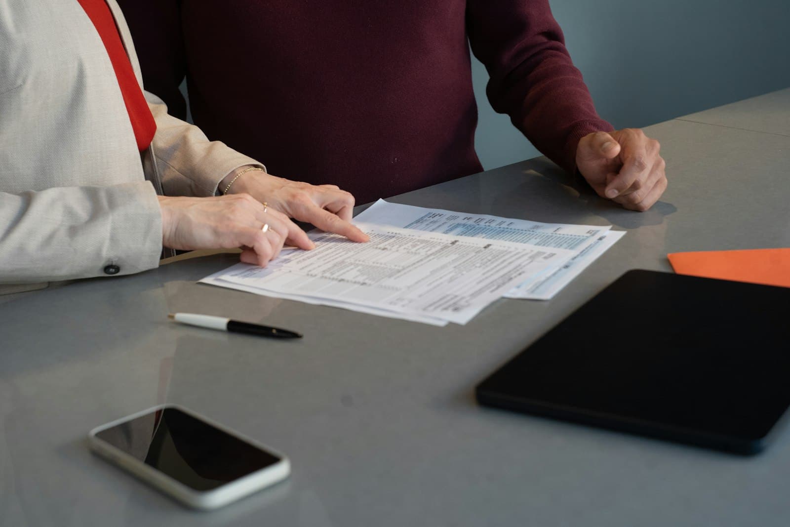 Dos personas revisan documentos sobre una mesa de oficina